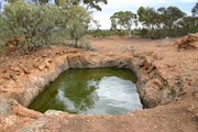The largest of a number of gnamma holes alongside the road at 