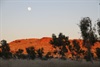 The sun on the hill behind with the moon still setting